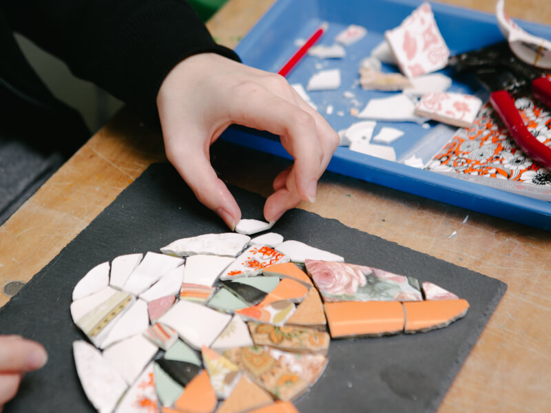 Hands arranging a cat-shaped mosaic